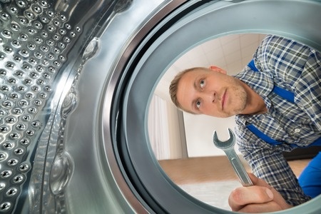 appliance repair technician looking inside the washer