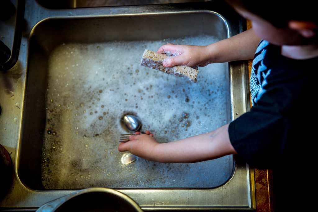 Image of a child washing dishes by hand